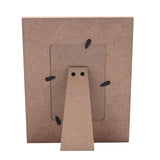 Rear view of the wooden 6 x 4in photo frame showing MDF backing, rectangular photo opening, foldout triangular stand, and black turn clips, on a white background.