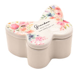 White butterfly-shaped glass trinket box with floral lid reading "Grandma, Never forget how LOVED you are," on a plain white background.