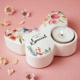 White glass butterfly-shaped tealight candle holder with watercolour floral design and "You are so VERY Special" script, lit tealight in one wing, on pink background.