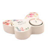 White glossy ceramic butterfly-shaped tealight candle holder with "Nan" text and watercolour floral design, a lit tealight in one wing, set on a plain white background.