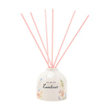 Off-white ceramic reed diffuser with rounded body, "You are the Loveliest" script and watercolour floral print, topped with six pink reeds, on a plain white background.