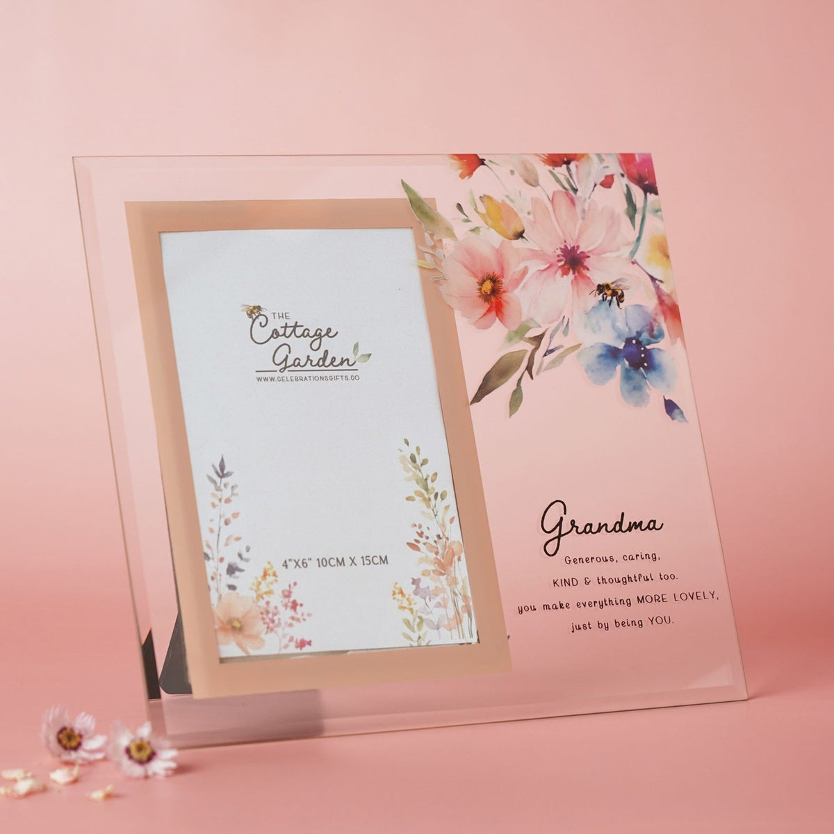 Clear glass photo frame with peach-bordered 6x4in opening, floral and bee print, and "Grandma" verse in script, set against a pink background.