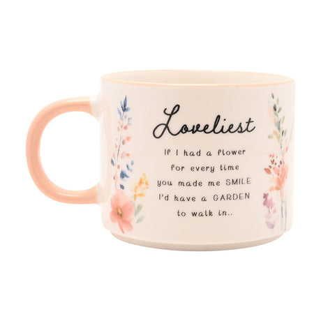 White stoneware mug with peach handle, featuring "Loveliest" script and a verse surrounded by watercolour wildflowers in coral, blue and yellow, on a plain white background.