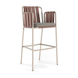 Teja outdoor bar stool with arms, featuring a beige aluminium frame, rust-toned woven rope back and arms, and a grey seat cushion, shown on a plain white background.