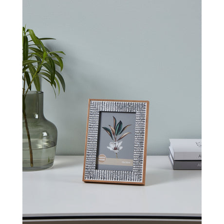 Temerloh Photo Frame with wood-effect edge and grey-white textured border, holding a botanical print, displayed on a white desk beside a glass vase and books.