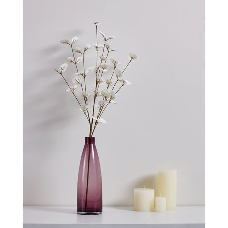 Tepaling Artificial Leaf Spray in White, rounded leaves on slender brown branches, displayed in a purple glass vase beside ivory candles against a light grey wall.