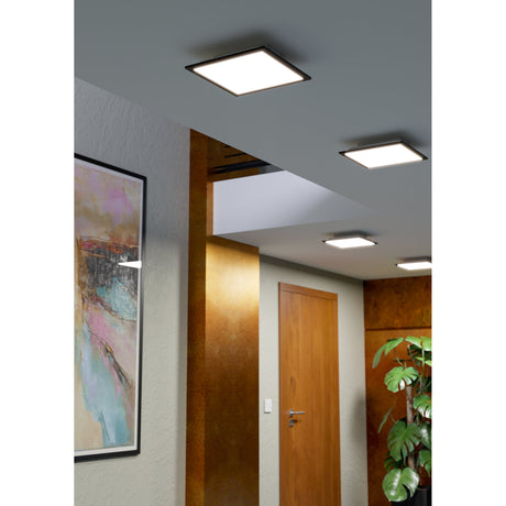 Tesvelle Smart LED Panel Light in black, square ceiling fixtures with slim frames shown installed in a hallway alongside wooden doors and artwork.