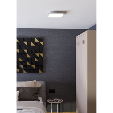 Tesvelle square LED ceiling panel light in white, illuminated on a bedroom ceiling above a bed, geometric wall art, and wardrobe.