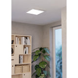 Square white LED ceiling panel light, Tesvelle 39.3 x 39.3cm, flush-mounted in a hallway near a bookshelf, plant, and window.