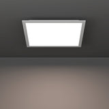 Tesvelle square LED ceiling panel light, 39.3 x 39.3cm, with white steel frame and glowing white plastic shade, mounted flush on a dark ceiling.