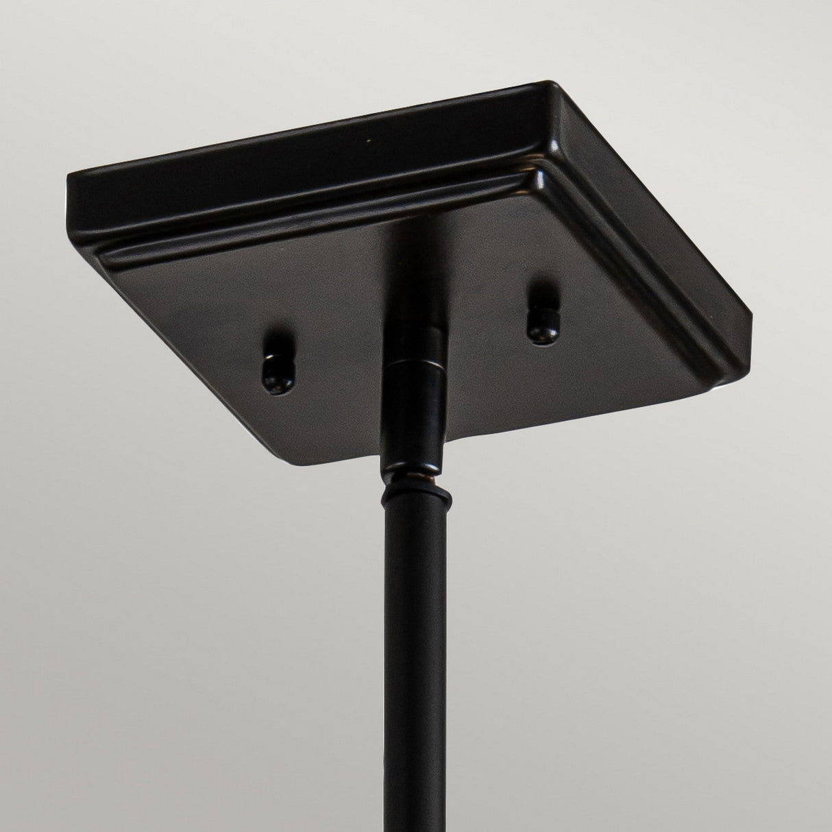 A close-up view of the Alderley 2 Light Trio Mount Tiffany Pendant in a vintage bronze finish features a minimalist design with Art Deco elegance, characterized by its smooth surface and a rod extending downwards, set against a plain white background.