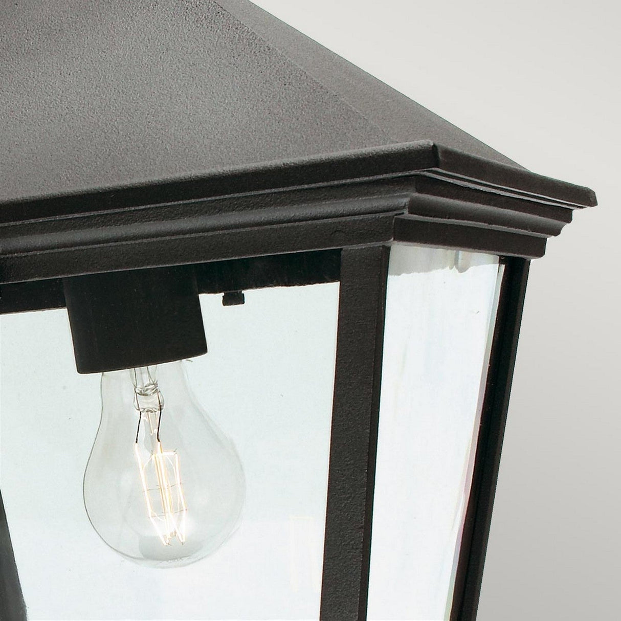 Close-up view of the Turin Large Outdoor 1 Light Chain Pendant in black, showcasing its vintage-style design with a clear glass panel and a visible incandescent bulb inside. The pendant features a dark metal frame, exuding vintage charm with its peaked top, while its durable aluminum fixture ensures lasting elegance.