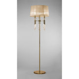 The Tiffany 6 Light Crystal Floor Lamp features a brass finish, bronze shade, slender pole, round base, and elegant hanging crystal accents beneath the shade. It stands against a plain gray background.