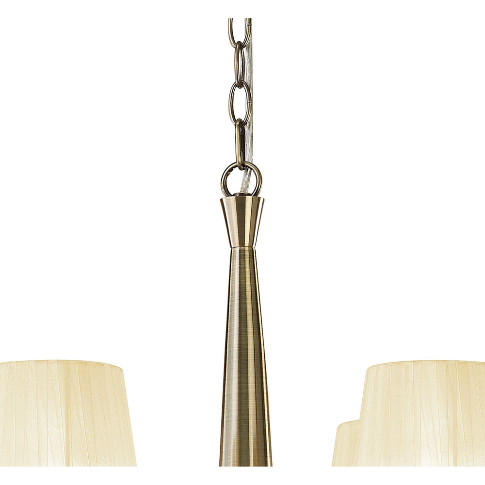 Close-up of the Tiffany chandelier's antique brass central column and chain suspension, with two cream pleated fabric shades visible at the lower edges.