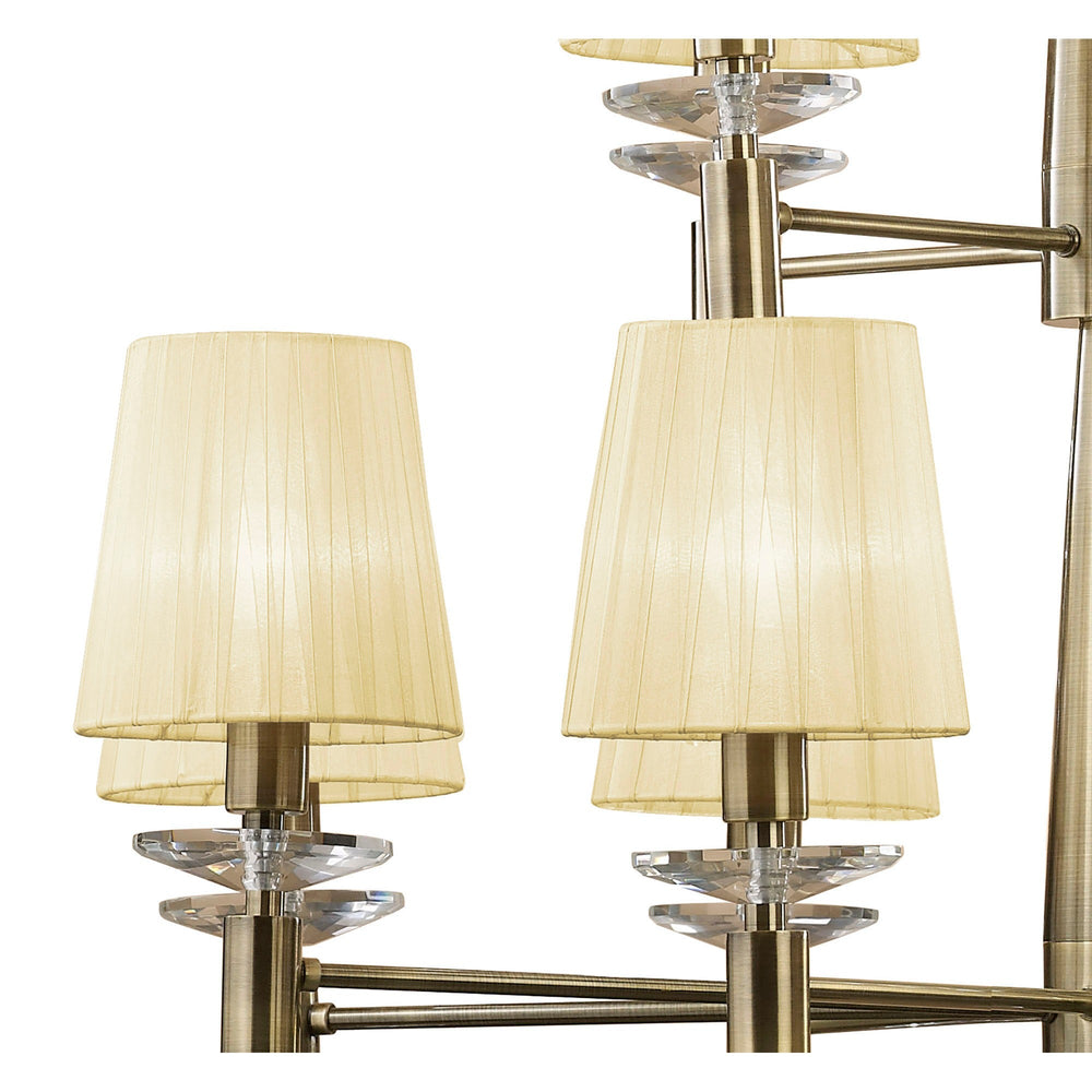 Close-up of Tiffany chandelier arms in antique brass with cream pleated fabric shades and faceted crystal accents.
