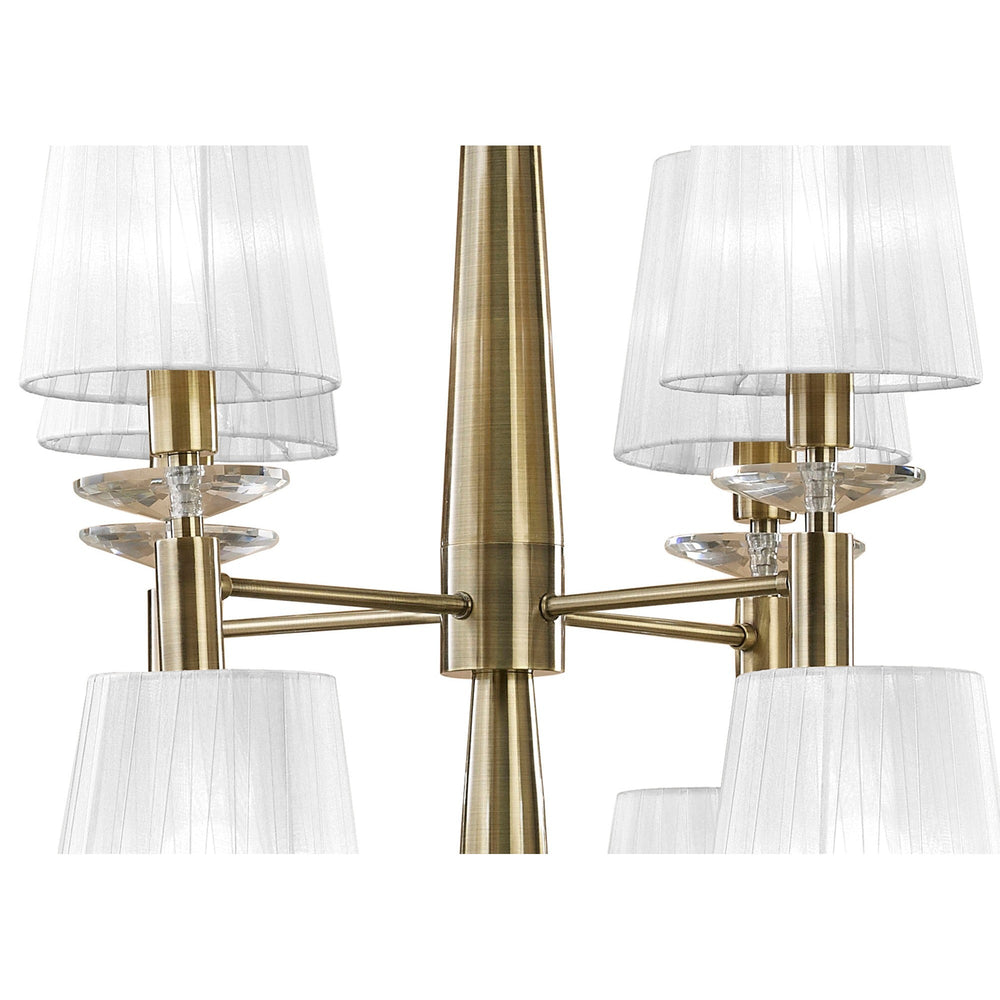 Close-up of Tiffany 12 Light chandelier showing antique brass arms, pleated white fabric shades, and faceted crystal droplets beneath each arm.