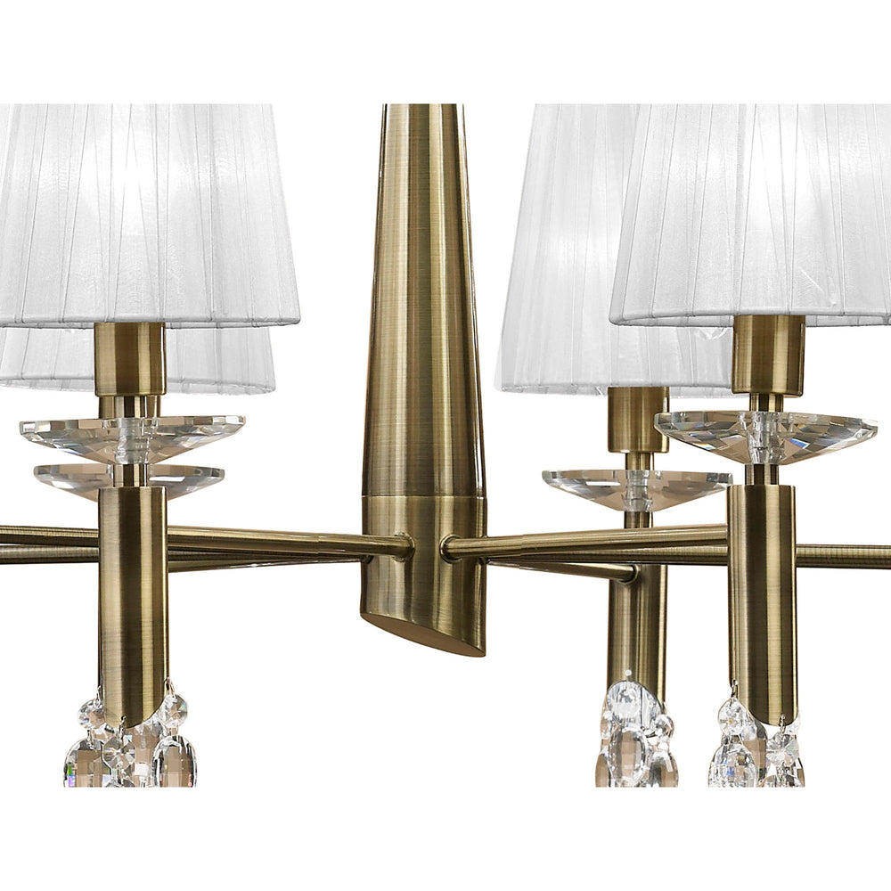 Close-up of Tiffany chandelier arms in antique brass with pleated white fabric shades, faceted crystal accents and droplets.