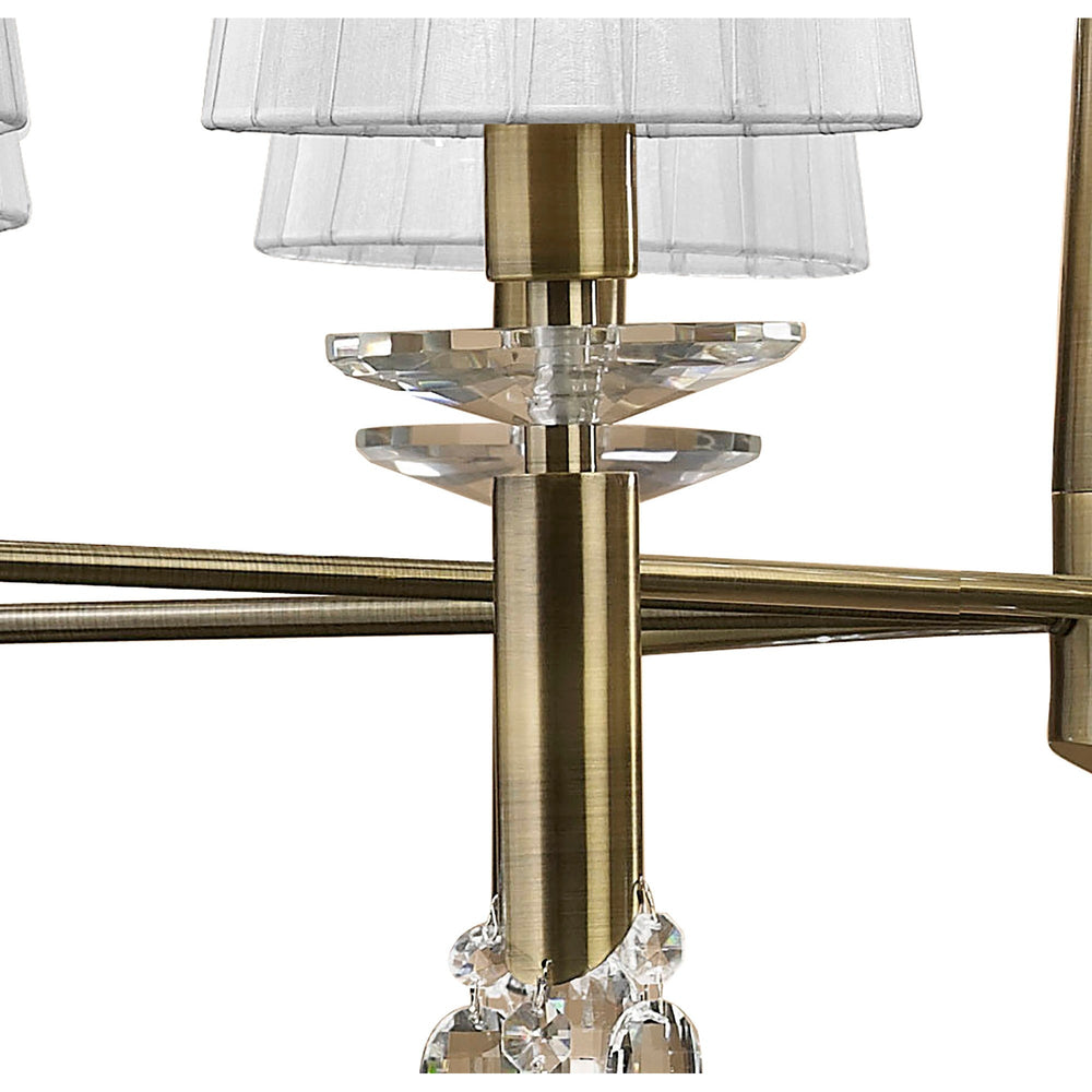Close-up of the Tiffany chandelier showing antique brass arms, faceted crystal accents, and pleated white fabric shades on the upper tier.