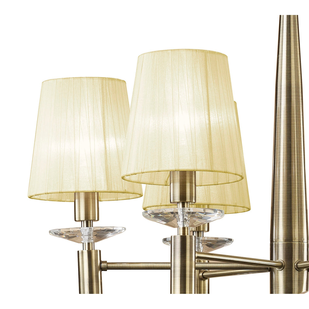 Close-up of Tiffany chandelier arms in antique brass with cream pleated fabric shades and faceted crystal droplets beneath each bulb holder.