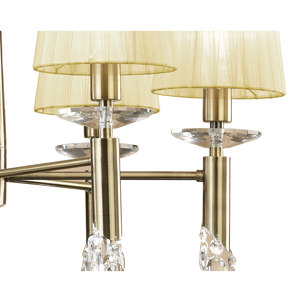 Close-up of Tiffany 6 Light Crystal Chandelier arms in antique brass with cream pleated fabric shades and faceted crystal accents.