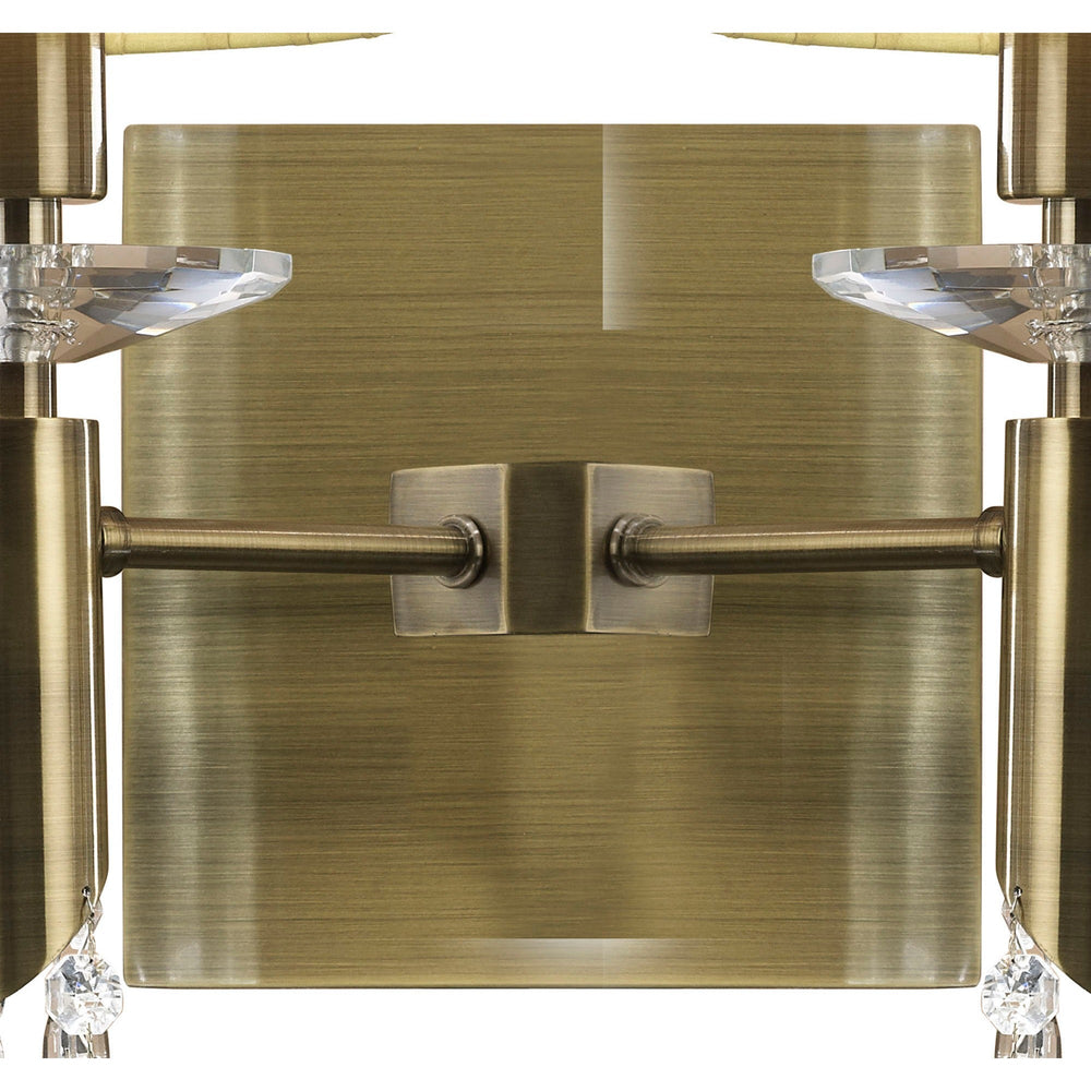 Close-up of the Tiffany wall light's antique brass backplate with central rocker switch, flanked by crystal bobeches and cream shade bases.