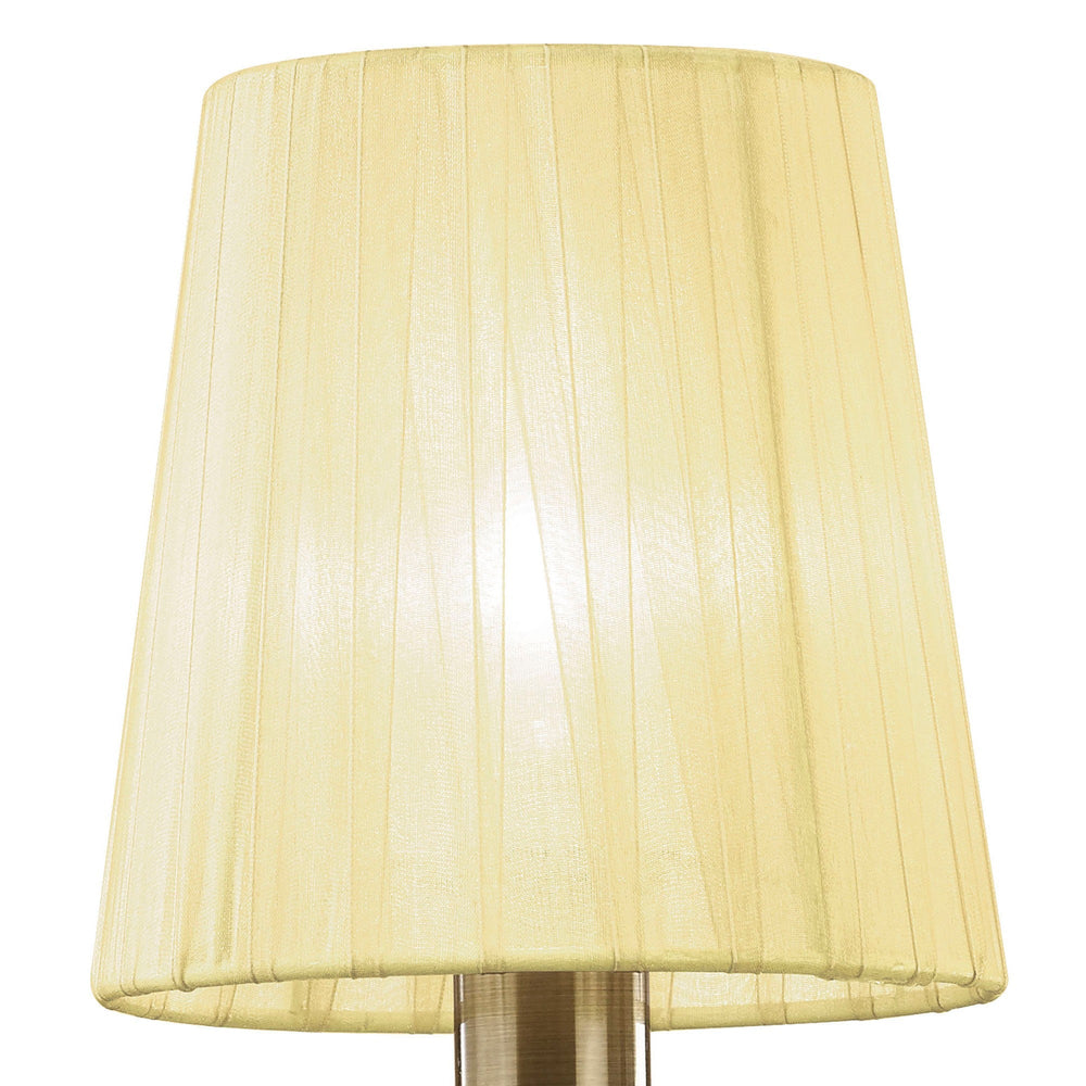 Close-up of cream pleated fabric shade on Tiffany wall light, illuminated bulb visible through the fabric above an antique brass fitting.