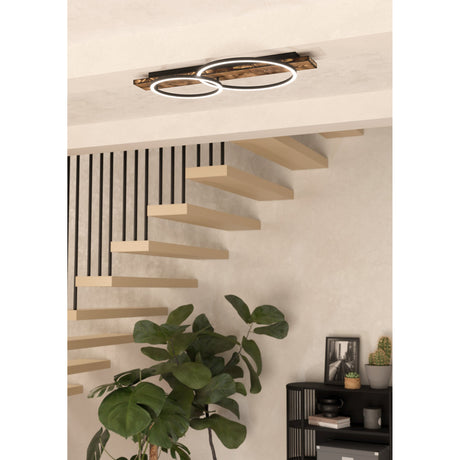 Timarne 2 Light Flush Ceiling Light mounted above a staircase, featuring a rustic brown wooden beam with two overlapping black rings and white LED diffusers, 12W.