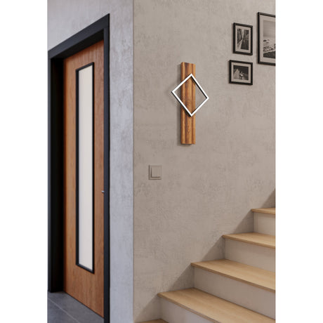 Timarne LED Wall Light with rustic brown wood backplate and black diamond-shaped frame, mounted beside a staircase on a textured beige wall near framed photos.