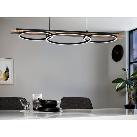 Timarne Pendant Light 25W in black and rustic brown, featuring three overlapping LED rings beneath a wooden beam, shown suspended above a dining table in a grey living space.