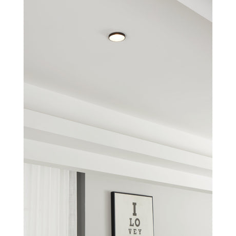 Tomelle Downlight in white and black recessed into a pale ceiling, round aluminium body with a black inner ring, shown in a room with exposed beams.