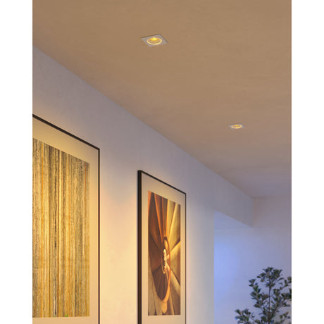 Tomelle square recessed LED downlights in white, shown recessed into a hallway ceiling with warm light illuminating framed artwork on the wall below.