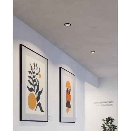 Tomelle round recessed LED downlights, 9.3cm, black finish with white inner ring, installed in a grey ceiling above framed artwork in a corridor setting.