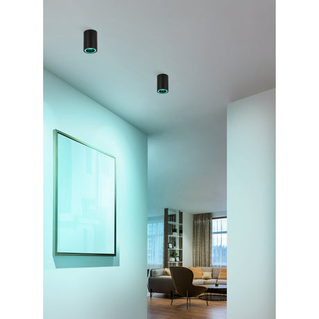 Two Tomelle Smart LED flush ceiling lights in black aluminium with white trim rings, shown recessed close to the ceiling above a hallway with teal-toned accent lighting.