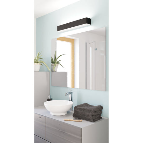Tomessa LED Bathroom Wall Light in black and white, a slim rectangular steel bar fixture mounted above a mirror, illuminating a grey bathroom vanity with basin and sink.