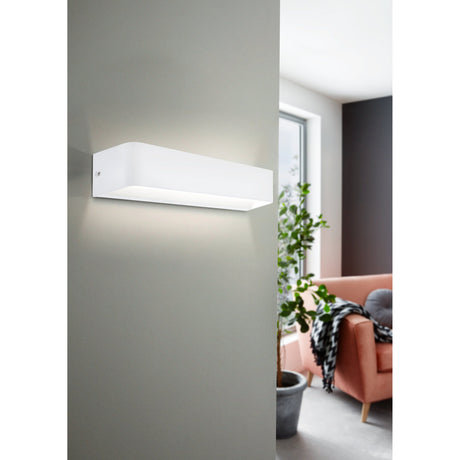 Tomessa LED Wall Light 36.5cm in white, a slim rectangular aluminium fixture with rounded ends, mounted on a grey wall in a living room, casting warm up and down light.