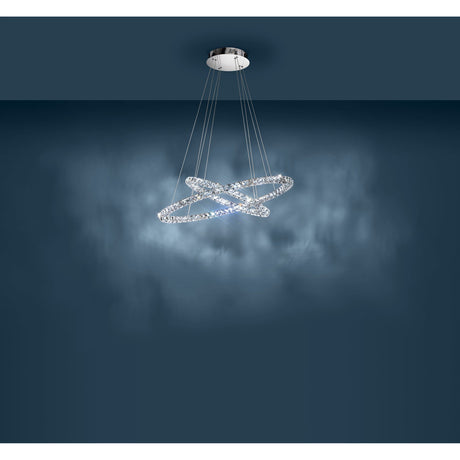 Toneria LED pendant light with two crossed chrome rings set with faceted clear glass, suspended on fine wires from a round ceiling plate, shown against a dark blue background.