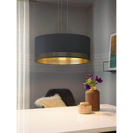 Tonvorne 3-light fabric drum pendant in black with gold interior and cut-out pattern band, shown hanging above a desk in a grey-walled living space.