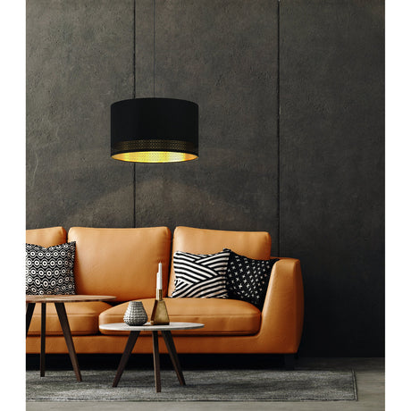 Tonvorne Fabric Pendant Light in black, a drum-shaped ceiling light with gold-lined interior, shown lit above an orange leather sofa with patterned cushions in a living room.
