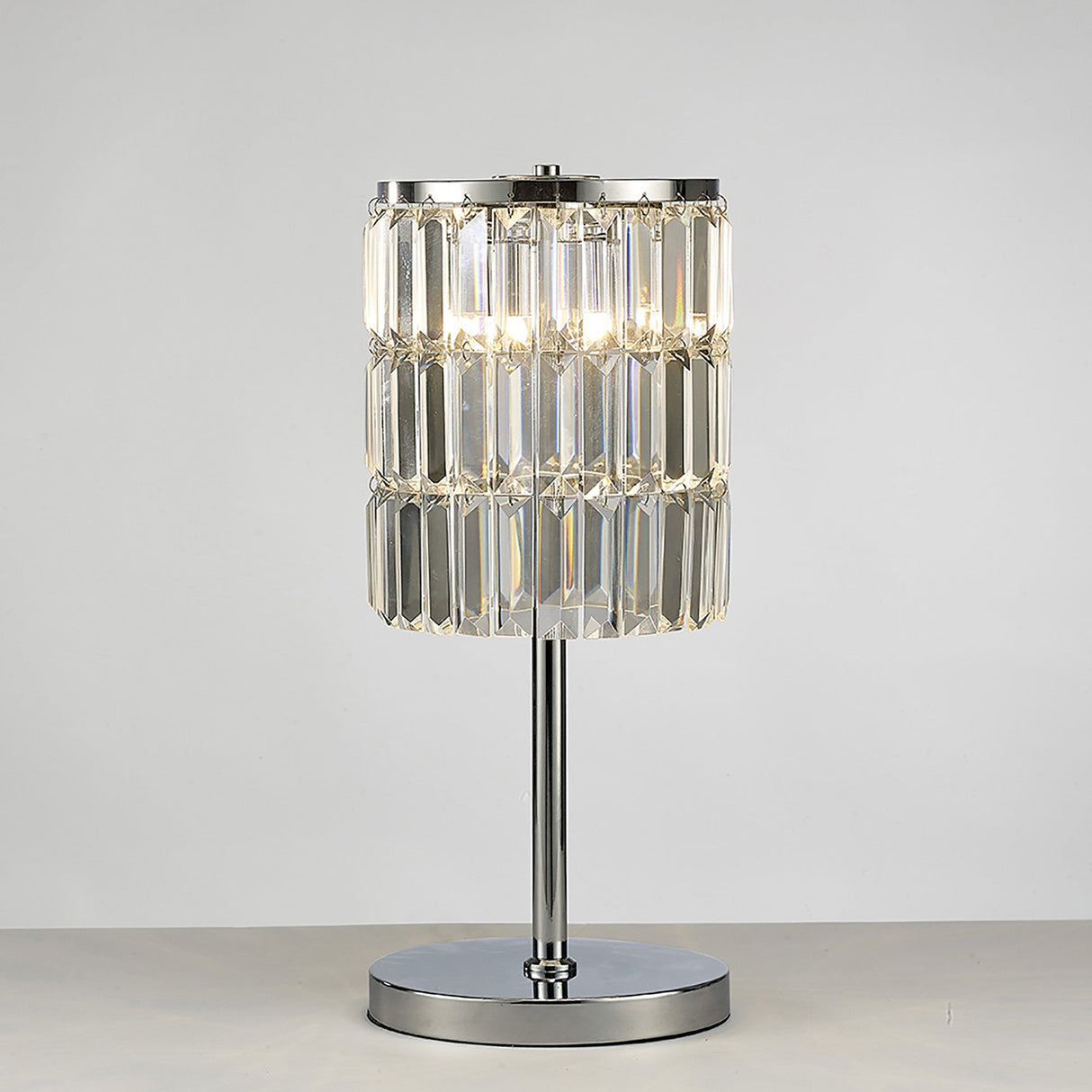 The Torre 3 Light Crystal Curtain Table Lamp features a polished chrome base and stem with a cylindrical shade made of vertical crystal prisms, displayed on a light surface against a plain background.
