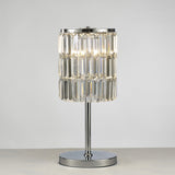 The Torre 3 Light Crystal Curtain Table Lamp features a polished chrome base and stem with a cylindrical shade made of vertical crystal prisms, displayed on a light surface against a plain background.