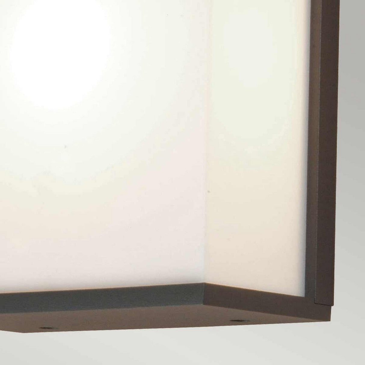 A close-up of the Torsten 1 Light Outdoor Large Wall Light in a graphite finish showcases its modern, square shape with a frosted glass cover and sleek metallic edges, softly illuminating the area. The image highlights its clean lines and minimalist design.