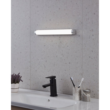 Tragacete 45cm LED bathroom wall light with cylindrical white diffuser and chrome end caps, mounted above a sink on a grey stone-effect wall.
