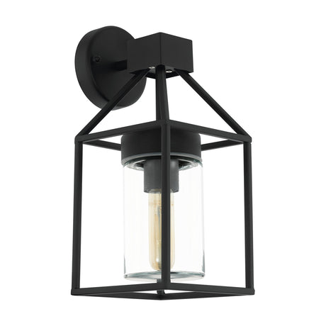 Trecate black outdoor wall light with an open lantern-style steel frame, angled arms, round wall plate, and a clear glass cylinder around the E27 bulb, shown on a plain white background.