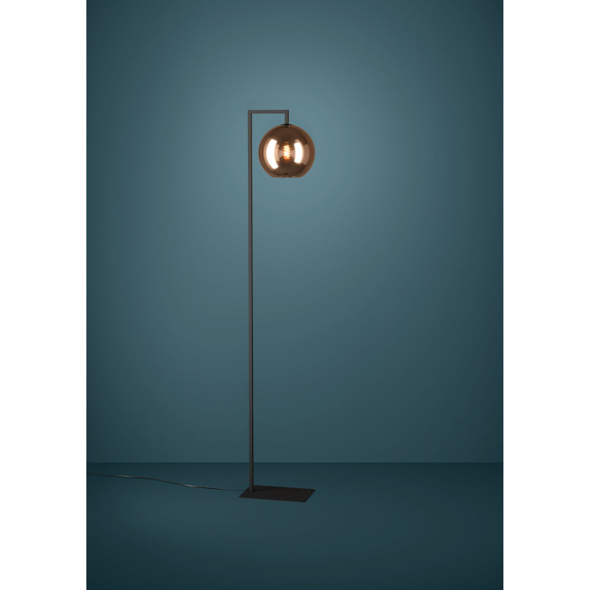 Trelbette Floor Lamp in black steel with a single copper globe glass shade on a right-angled arm, square base, shown against a dark teal background.