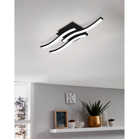 Trosmessa LED 3 Light Flush Ceiling Light in black, three wavy bars with white diffusers mounted close to a white ceiling above a styled grey shelf.