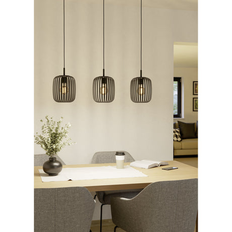 Trosvelle Linear Pendant Light in black steel with three slatted drum shades on individual cords, shown above a dining table with chairs and a vase.