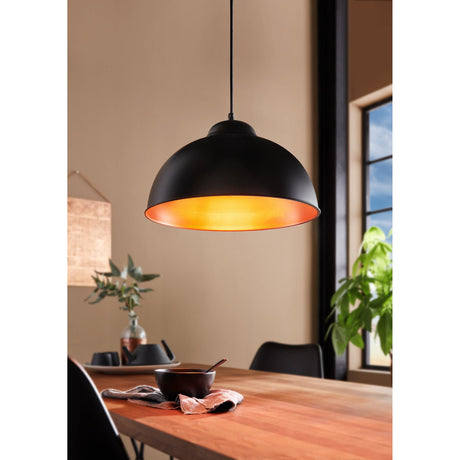 Truro 2 dome pendant light with black steel shade and copper interior, hung from a black cord above a wooden dining table in a living room setting.