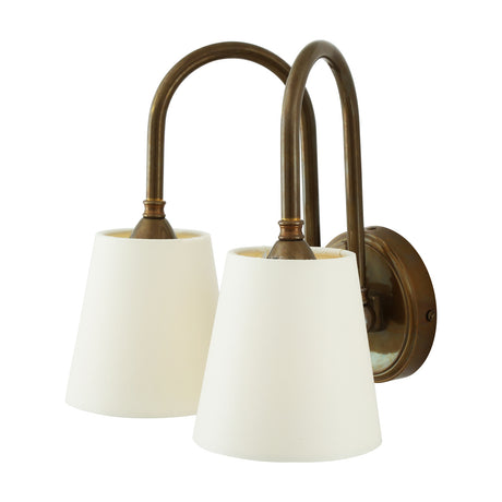 Uppsala Double Swan Neck Wall Light with two curved antique brass arms rising from a round backplate and holding tapered ivory fabric shades, shown on a plain white background.