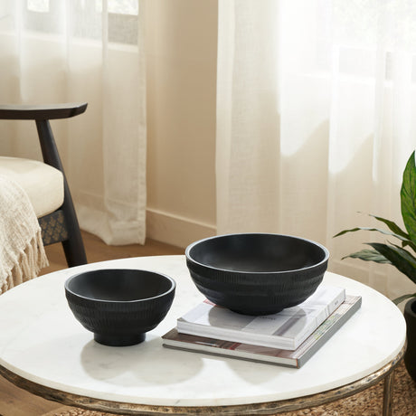 Uzak Mango Wood Decorative Bowl in black, shown with a smaller matching bowl on a round marble coffee table beside magazines in a living room setting.