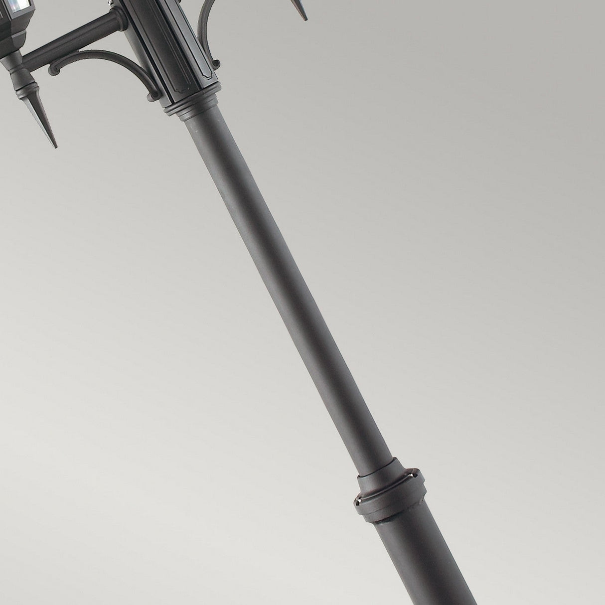 Close-up of the "Valencia 2 Light Twin Head Lamp Post" in black metal, featuring decorative elements perfect for garden pathways. Set against a plain gray background, its outdoor lighting details and structure are prominently visible.